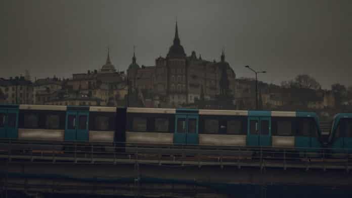 A moody view of Södermalm in Stockholm while the subway is going by over a bridge.