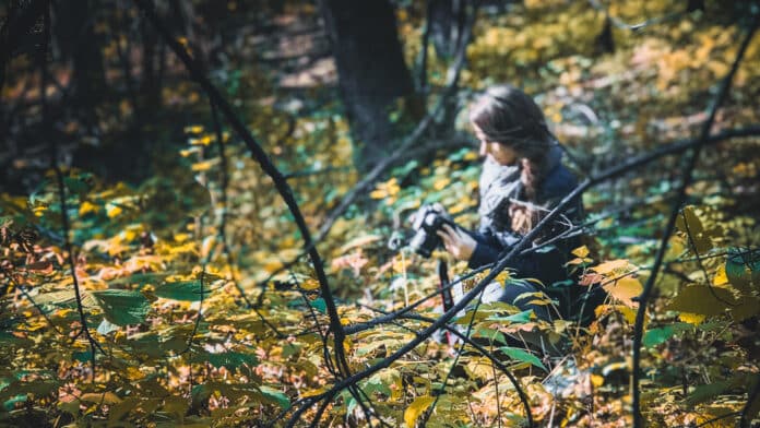 Lisah Silfwer with her camera in the forest.