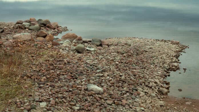 Rocky shore by calm water.