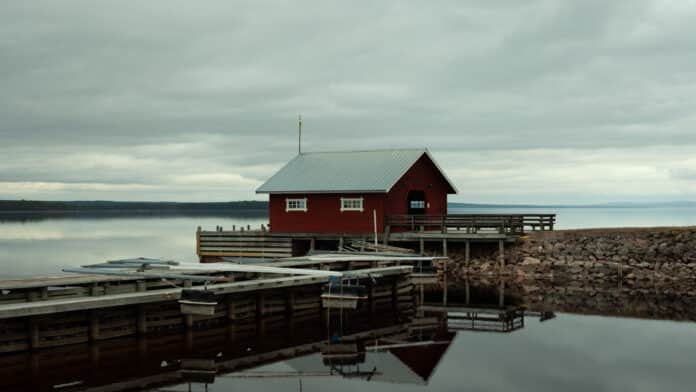 Red boathouse by calm waters.